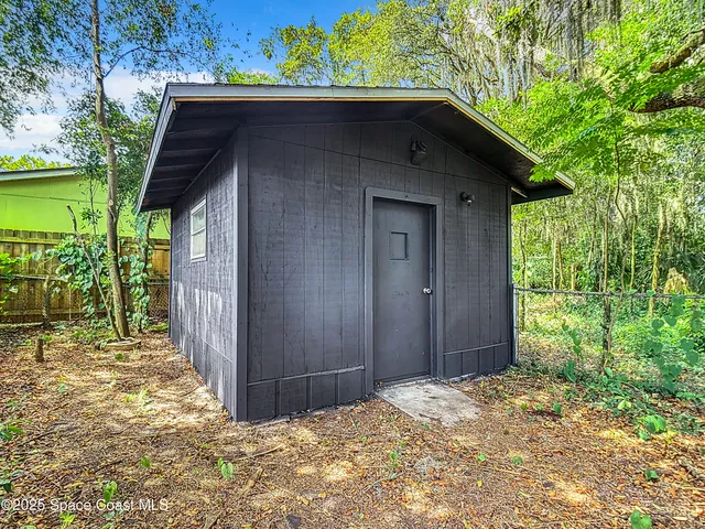 a backyard of a house with large trees and wooden fence