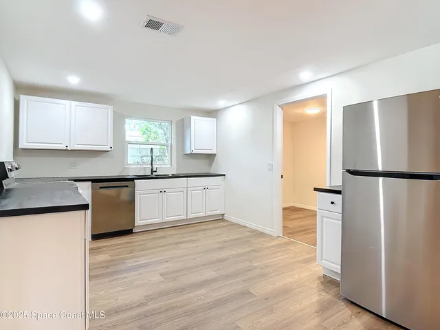 a kitchen with granite countertop a refrigerator and a stove top oven