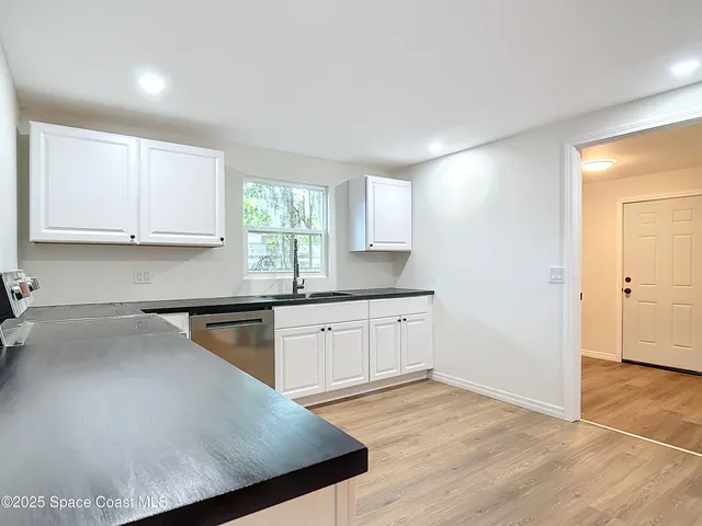 a kitchen with granite countertop a sink a stove cabinets and wooden floor