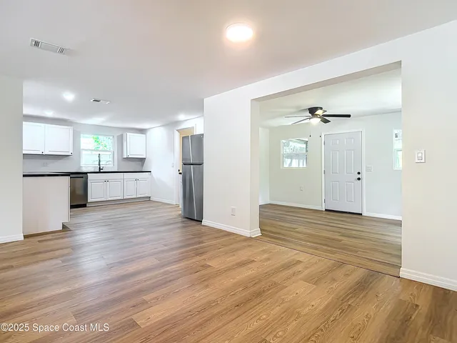 a view of a kitchen with wooden floor and a refrigerator