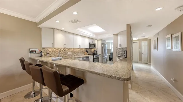 a kitchen with stainless steel appliances granite countertop a table chairs sink and cabinets