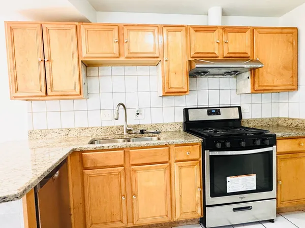 a kitchen with granite countertop a sink stove and cabinets