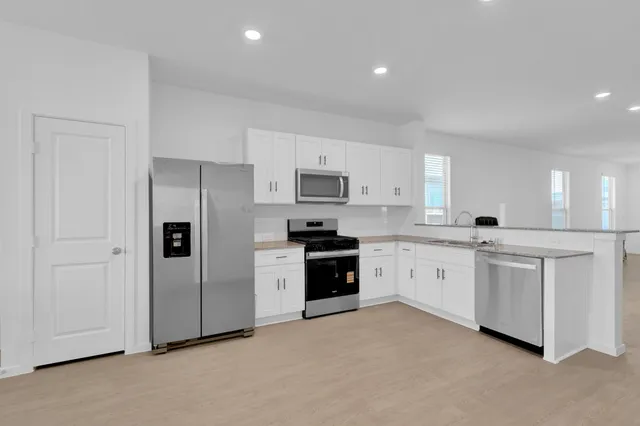 a kitchen with white cabinets and stainless steel appliances