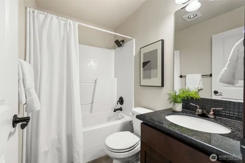 a bathroom with a granite countertop sink toilet a mirror a shower and a tub