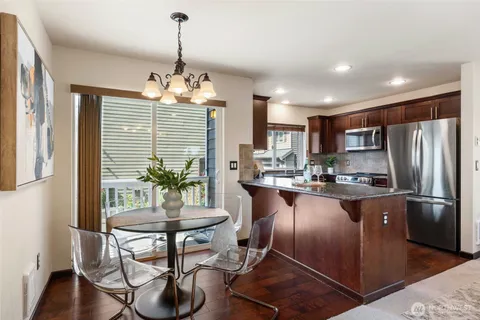 a kitchen with granite countertop a table chairs refrigerator and microwave