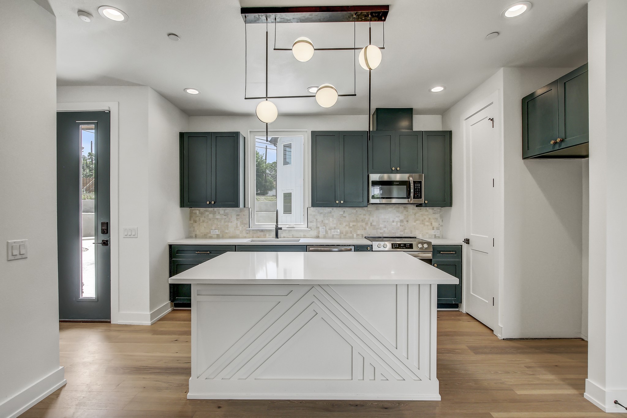 4127 East 12th Street, Unit 5 Austin, TX 78721 - Photo 1 of 33 Kitchen featuring a sink, appliances with stainless steel finishes, backsplash, light wood-style flooring, and light countertops