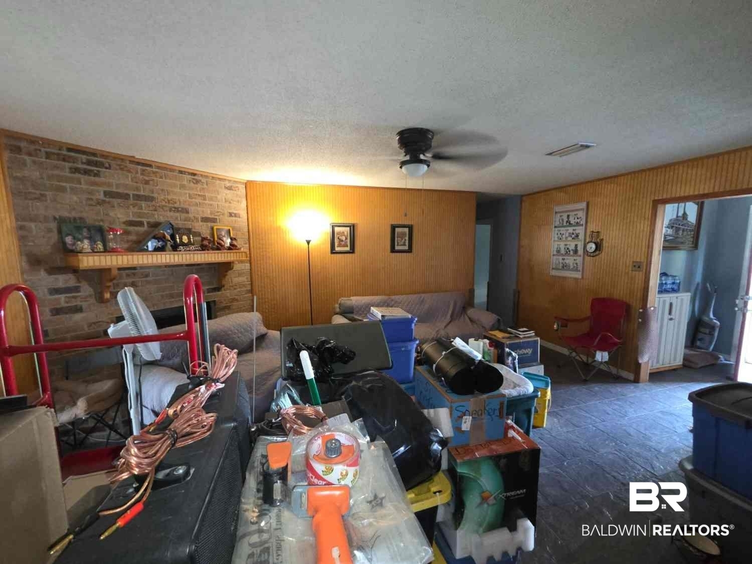 5120 West Celtic Drive Mobile, AL 36619 - Photo 11 of 27 Living area featuring wood walls, a fireplace, ceiling fan, and a textured ceiling