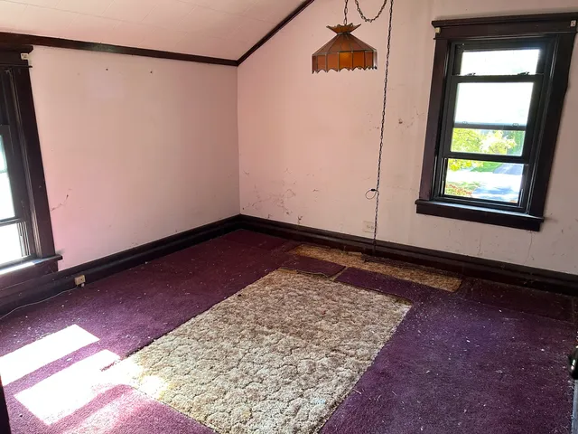 a view of an empty room with a rug and a window