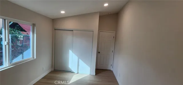 a view of a hallway with wooden floor and a bathroom
