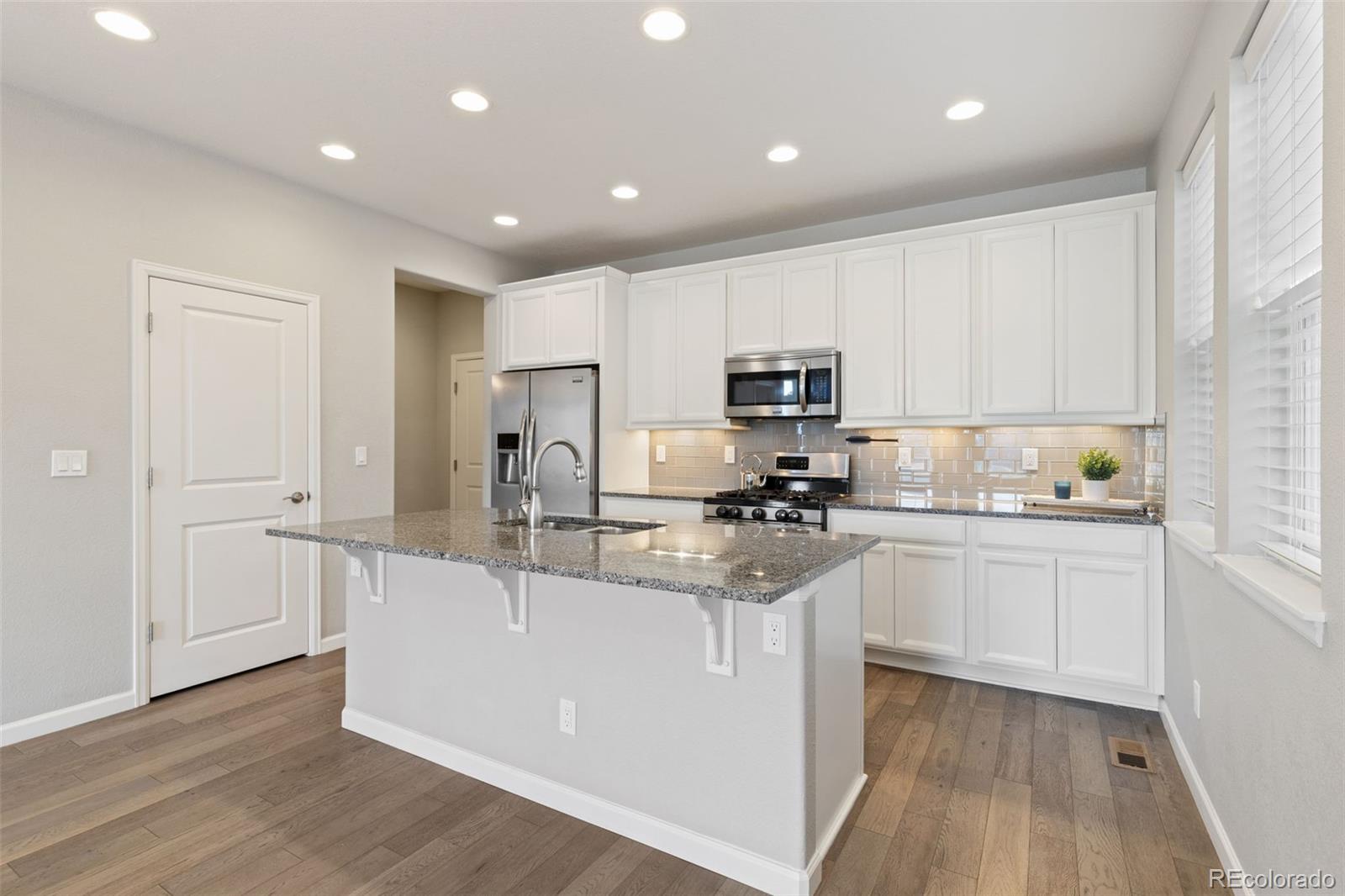 1338 Promontory Bluff View Colorado Springs, CO 80921 - Photo 11 of 28 a kitchen with kitchen island granite countertop a sink cabinets and wooden floor