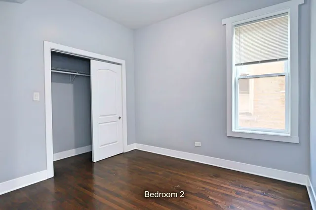 an empty room with wooden floor closet and windows