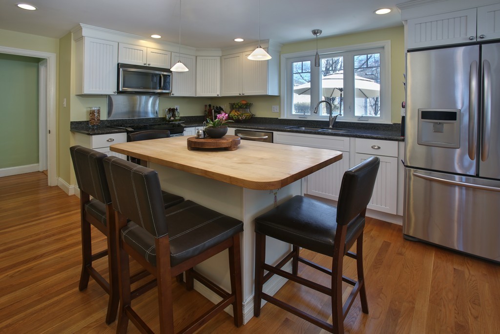 55 Bay State Road Arlington, MA 02474 - Photo 2 of 20 a kitchen with stainless steel appliances granite countertop a dining table chairs refrigerator and microwave