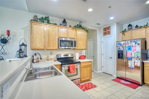 a kitchen with stainless steel appliances granite countertop a sink dishwasher and a refrigerator with wooden floor