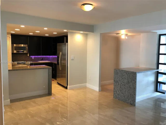 a view of an empty room with kitchen and a window