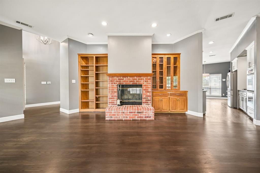 1380 Meandro Ria Lane Fairview, TX 75069 - Photo 8 of 39 Spacious open-concept living area featuring dark wood-finish flooring, soaring ceilings with recessed lighting, and a striking brick fireplace with integrated hearth