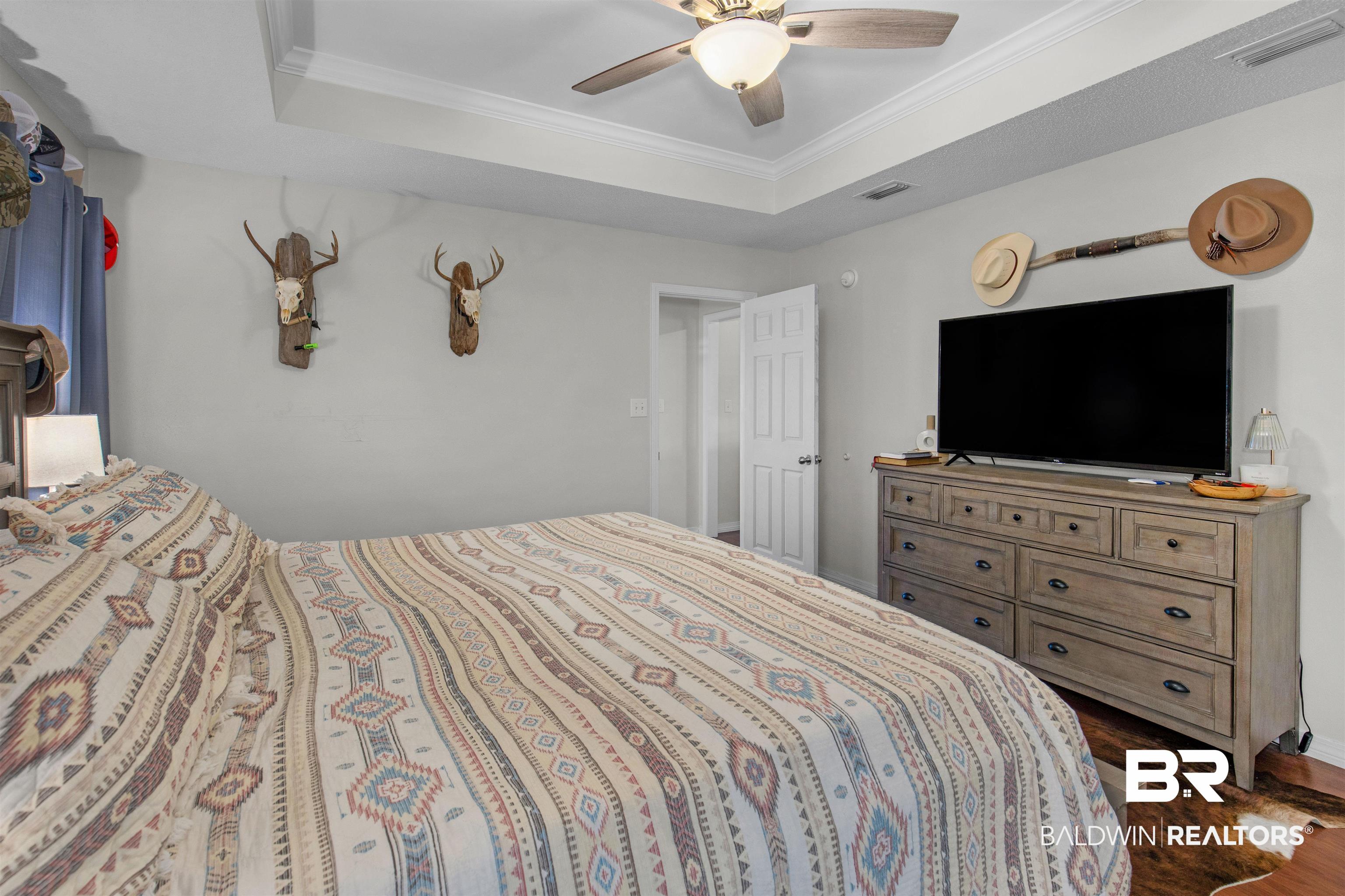 4950 Clealand Court Mobile, AL 36695 - Photo 10 of 20 Bedroom with ornamental molding, a raised ceiling, dark wood-style flooring, and a ceiling fan