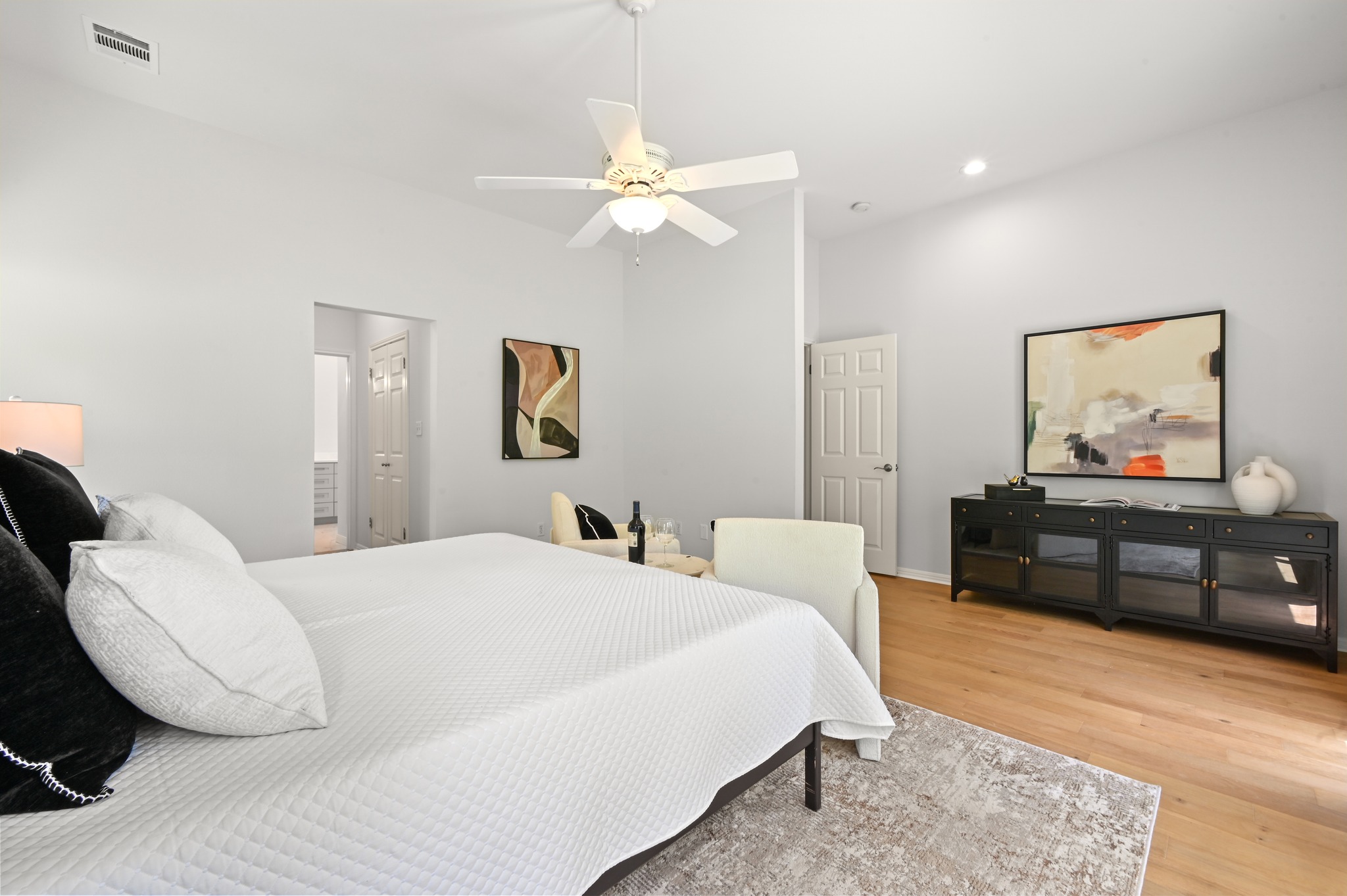 1107 Bowie Road Austin, TX 78733 - Photo 19 of 40 Natural light illuminates this spacious bedroom, featuring warm wood flooring and a refreshing ceiling fan.