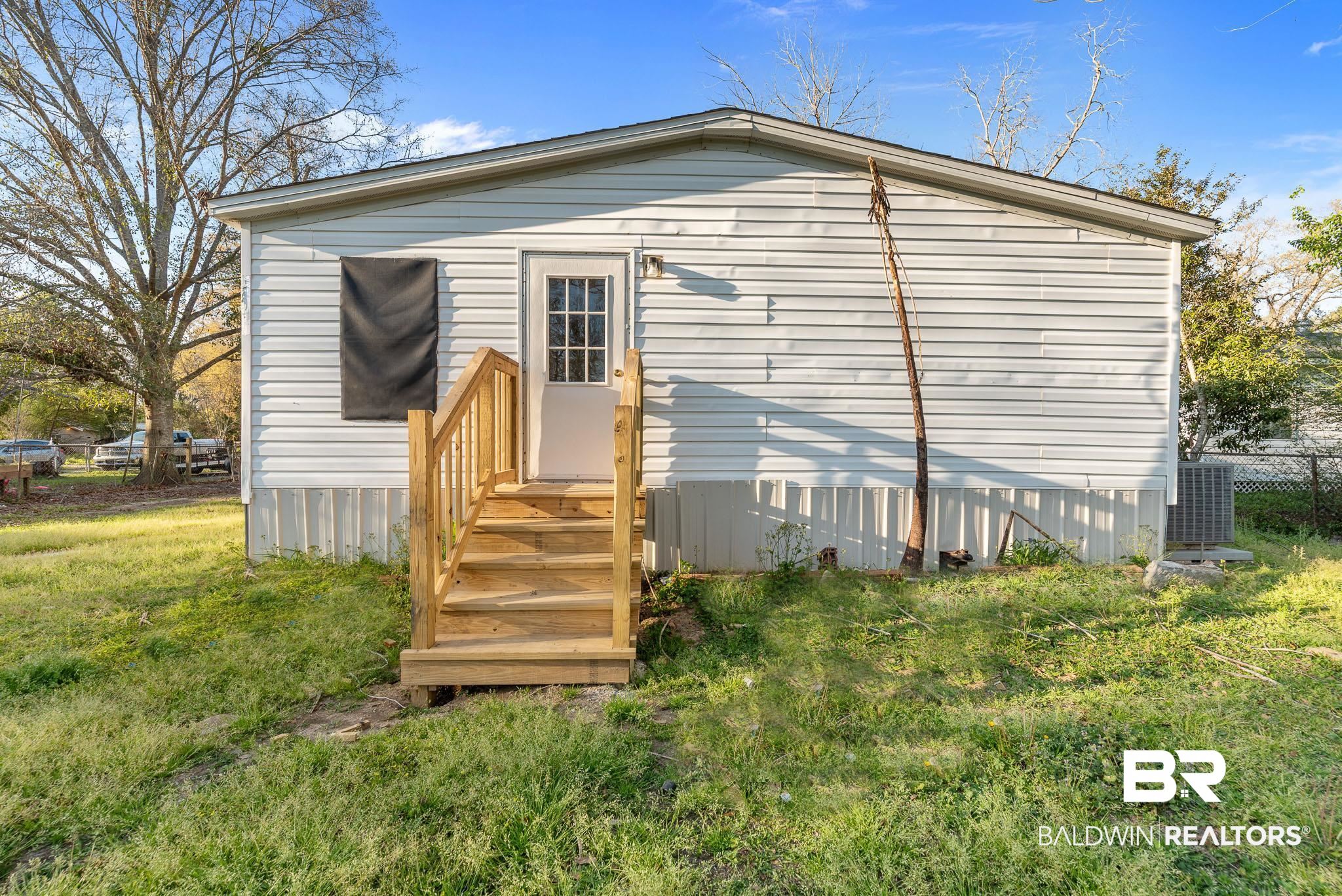 7695 Bermuda Drive Semmes, AL 36575 - Photo 4 of 27 Rear view of property with central AC unit, a yard, and fence