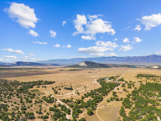 8 East Hollow Road, Unit 8 Spring City, UT 84662 - Photo 2 of 16 Expansive land with scattered trees, a visible dirt road, and distant mountain ranges under a blue sky