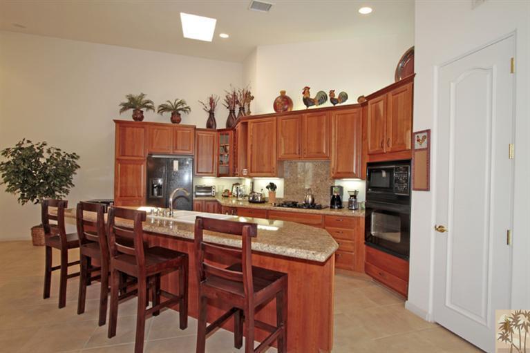 79175 Bermuda Dunes Drive Bermuda Dunes, CA 92203 - Photo 9 of 21 a kitchen with granite countertop a table chairs stove and cabinets