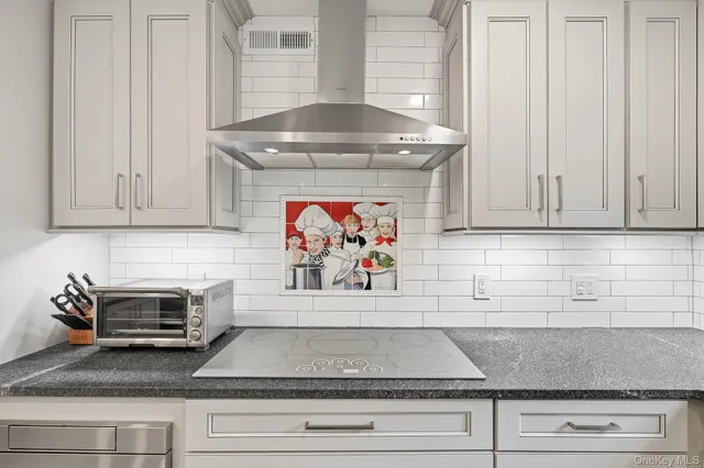 a kitchen with granite countertop white cabinets and a stove