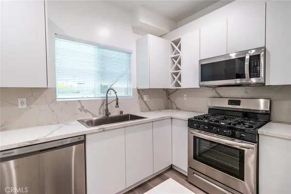 a kitchen with cabinets stainless steel appliances a sink and a window