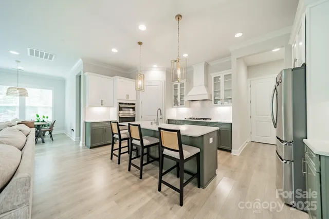 a kitchen with stainless steel appliances kitchen island granite countertop a table chairs refrigerator and microwave