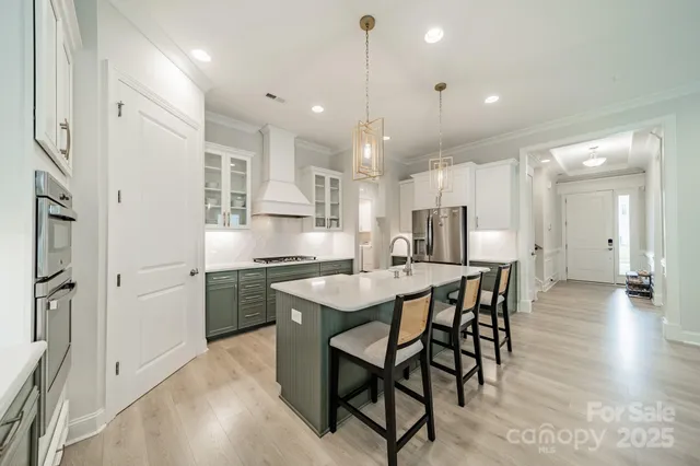 a kitchen with stainless steel appliances kitchen island granite countertop a table chairs sink and cabinets