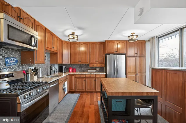 a kitchen with stainless steel appliances granite countertop a stove refrigerator and a microwave oven