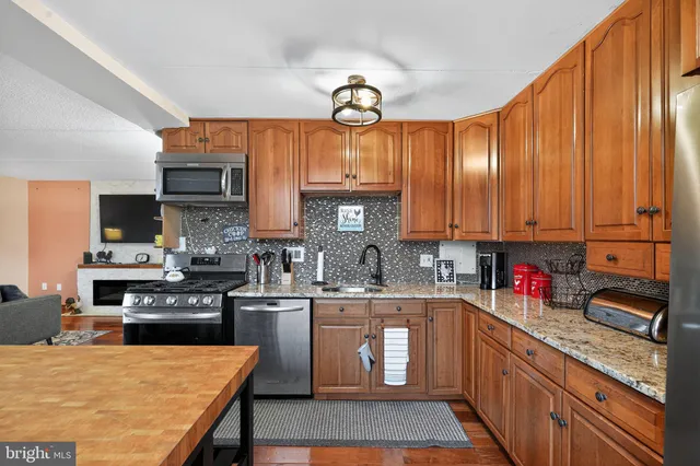a kitchen with stainless steel appliances granite countertop a sink dishwasher stove top oven and cabinets with wooden floor