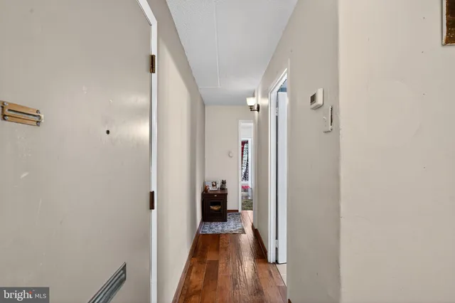 a view of a hallway with wooden floor and a bathroom