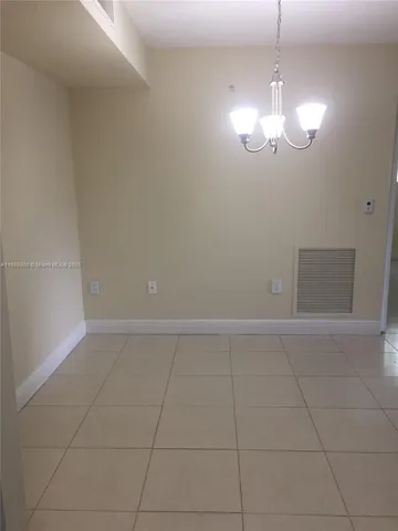 a view of an empty room with a chandelier fan