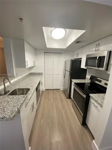 a kitchen with granite countertop a sink appliances and cabinets