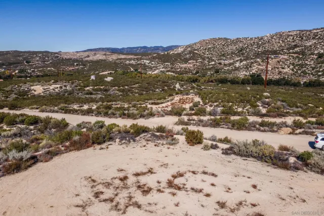 a view of a dry field with mountains in the background