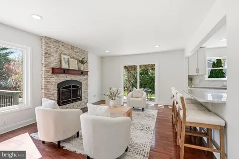 a living room with stainless steel appliances furniture a rug and a kitchen view