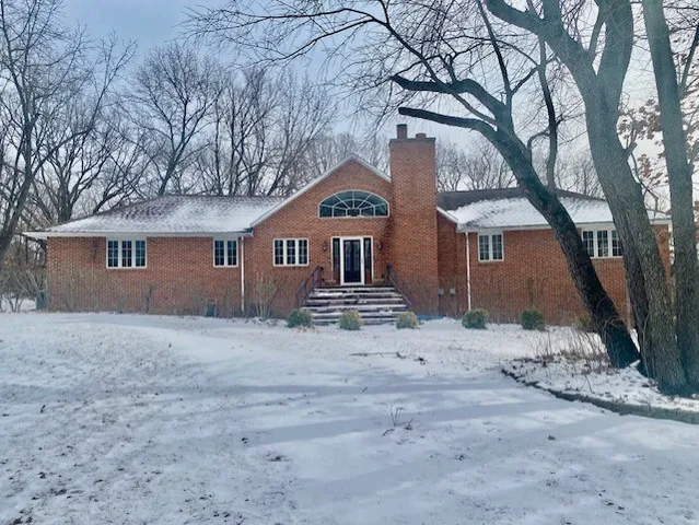 a front view of a house with a dirt yard and a large tree
