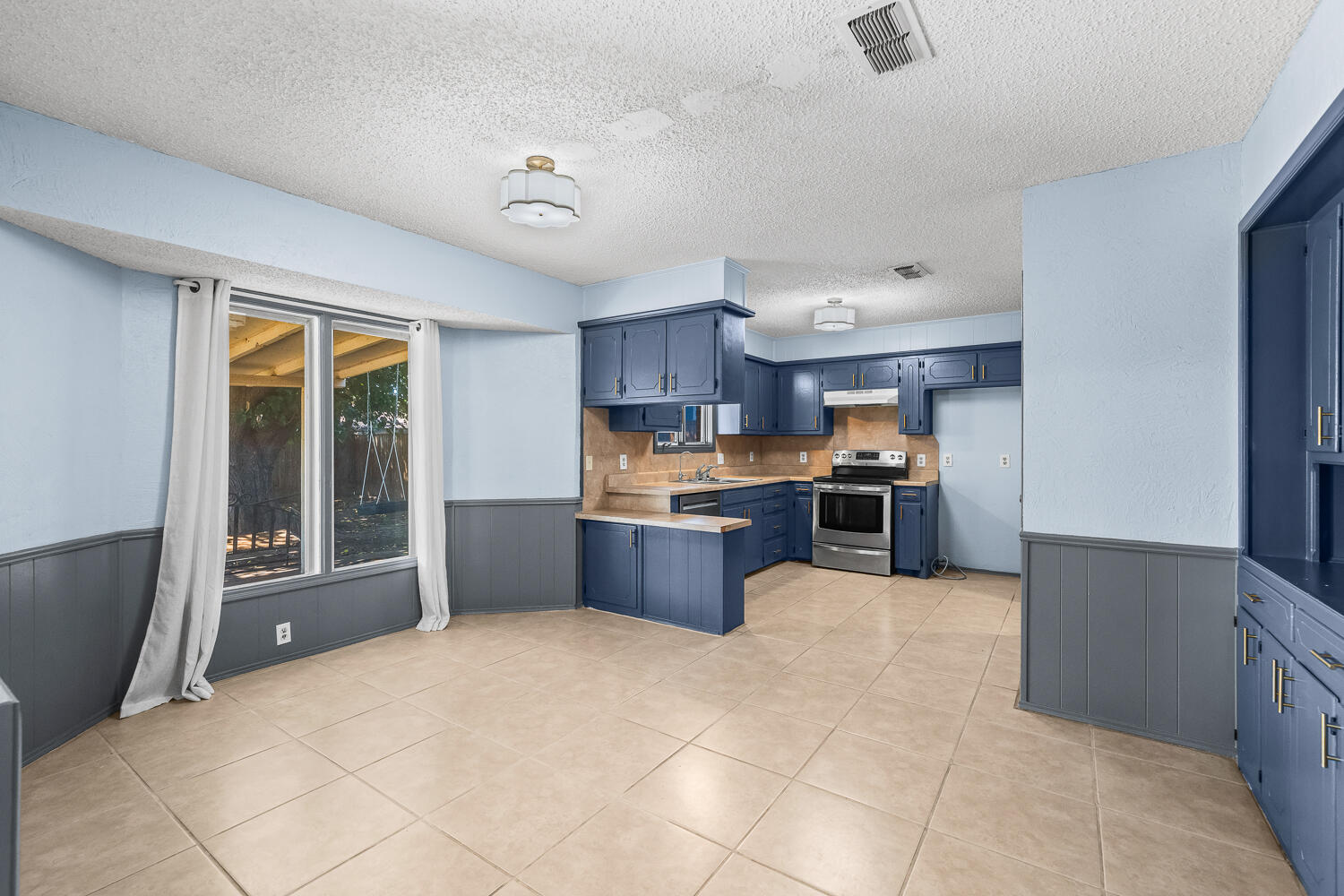 4809 72nd Street Lubbock, TX 79424 - Photo 7 of 34 a large kitchen with stainless steel appliances granite countertop a stove and a refrigerator