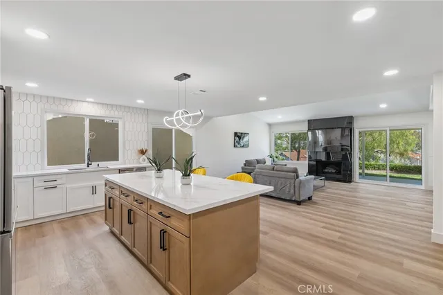 a large white kitchen with a stove a sink dishwasher and a refrigerator with wooden floor