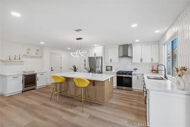 a large kitchen with kitchen island a stove a sink a refrigerator and white cabinets with wooden floor