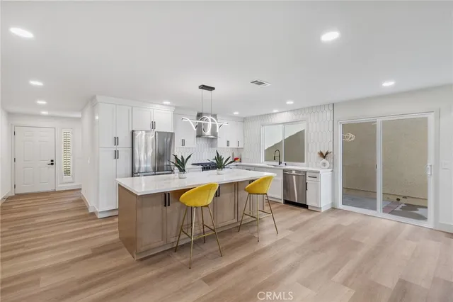 a large kitchen with stainless steel appliances granite countertop a large counter top a sink and a refrigerator