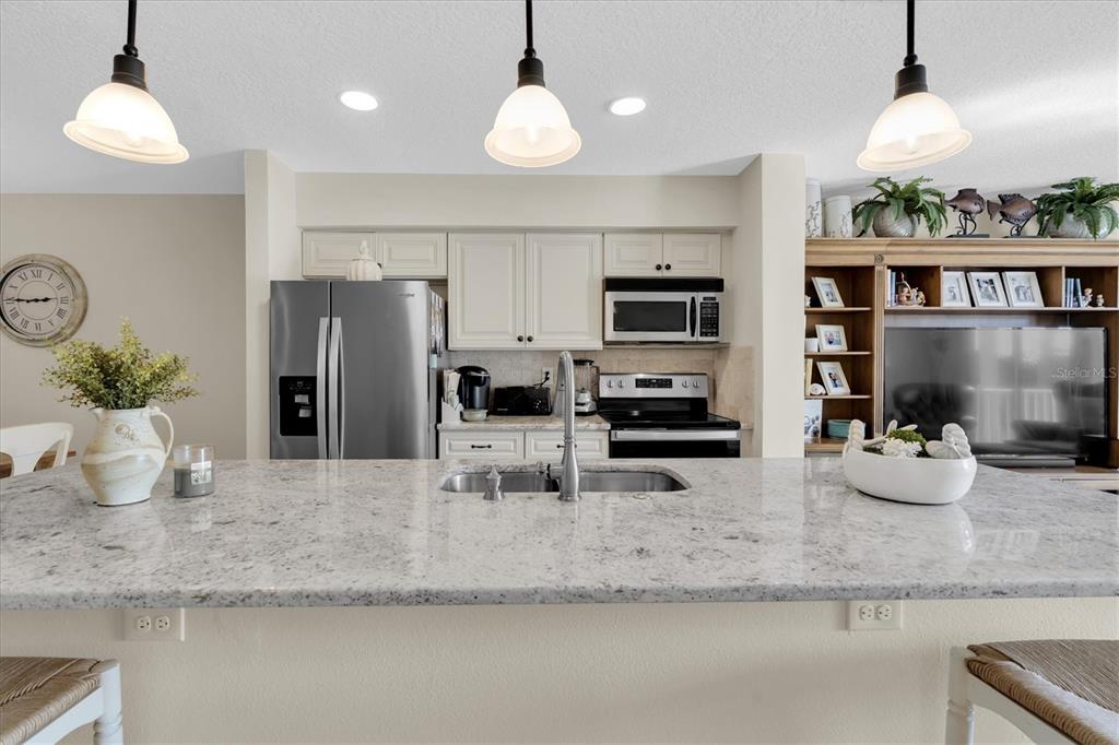 641 Garland Circle Indian Rocks Beach, FL 33785 - Photo 12 of 50 a kitchen with stainless steel appliances granite countertop a sink refrigerator and microwave