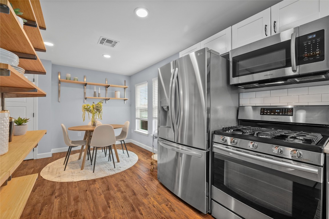 1191 Chicon Street Austin, TX 78702 - Photo 12 of 33 Kitchen with appliances with stainless steel finishes, tasteful backsplash, dark wood-type flooring, recessed lighting, and open shelves