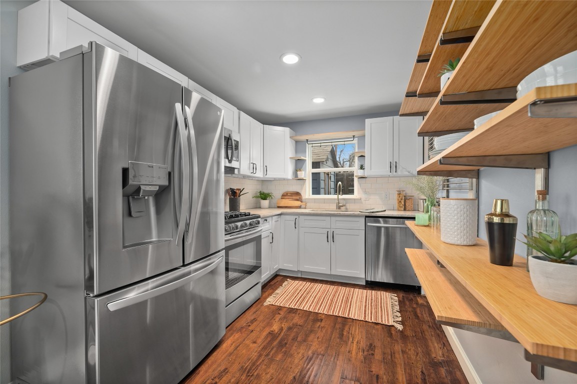 1191 Chicon Street Austin, TX 78702 - Photo 13 of 33 Kitchen with stainless steel appliances, open shelves, white cabinetry, dark wood-style floors, and recessed lighting