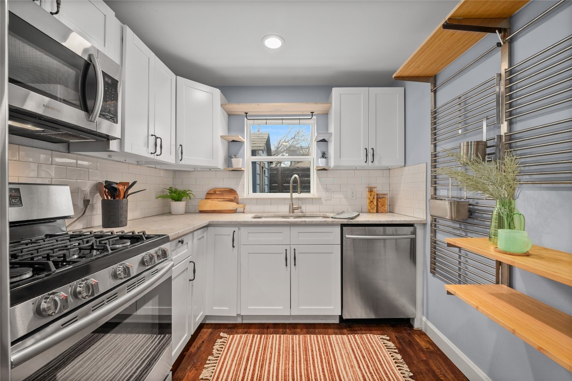 1191 Chicon Street Austin, TX 78702 - Photo 14 of 33 Kitchen with open shelves, stainless steel appliances, white cabinets, and dark wood-style flooring