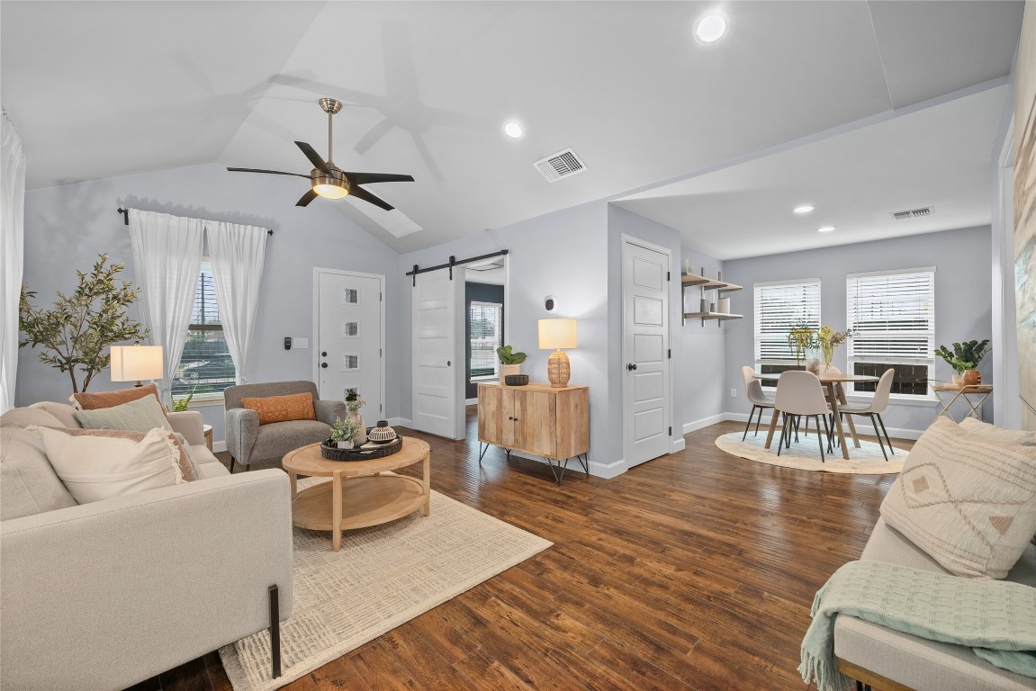 1191 Chicon Street Austin, TX 78702 - Photo 3 of 33 Living room featuring a barn door, ceiling fan, healthy amount of natural light, wood finished floors, and vaulted ceiling
