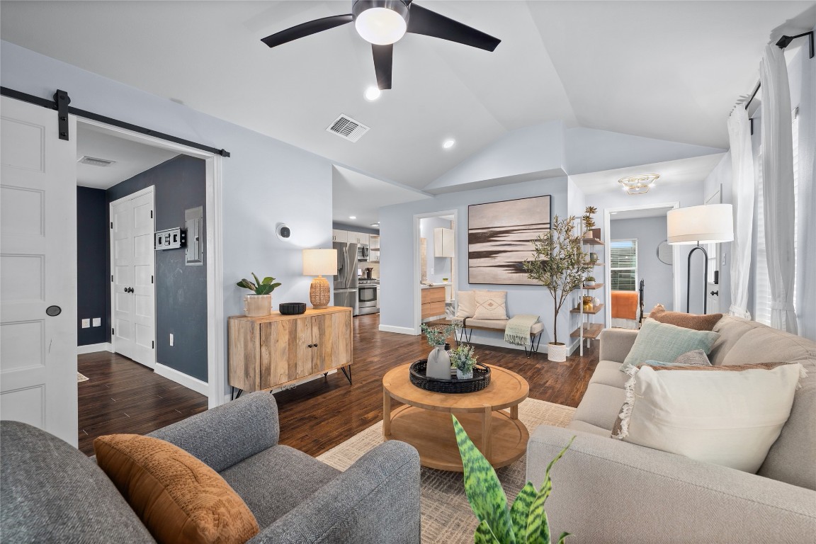 1191 Chicon Street Austin, TX 78702 - Photo 4 of 33 Living room with a barn door, wood finished floors, lofted ceiling, and a ceiling fan