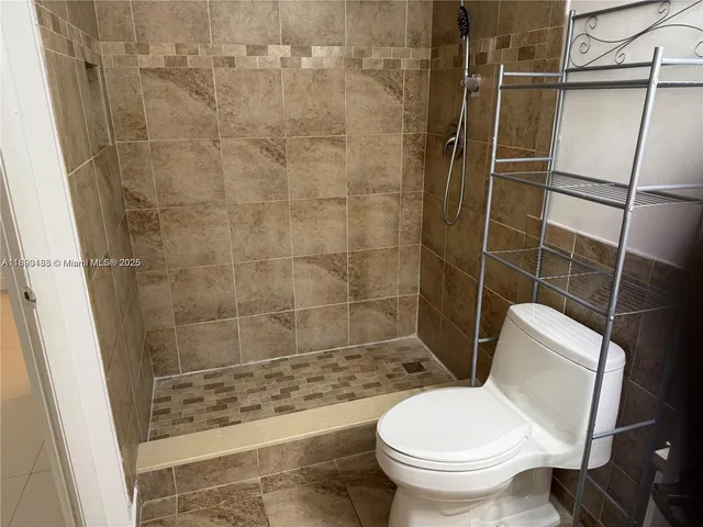 a white toilet sitting next to a shower