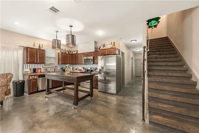 a view of kitchen with stainless steel appliances kitchen island refrigerator stove and wooden floor