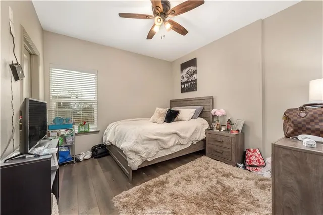 a bedroom with a bed large window with table and chair