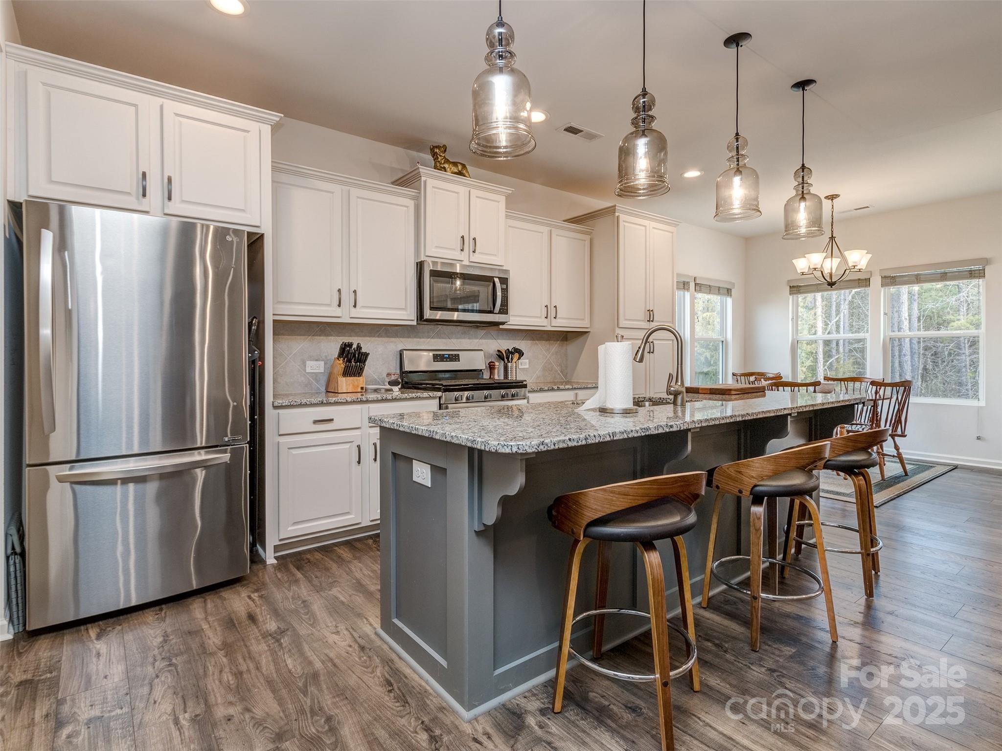5220 Admirals Landing Lancaster, SC 29720 - Photo 9 of 48 a kitchen with kitchen island granite countertop a table chairs refrigerator and microwave
